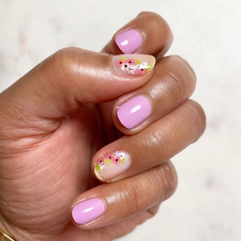 Design de unhas curtas com espaço rosa e negativo alternados com uma flor