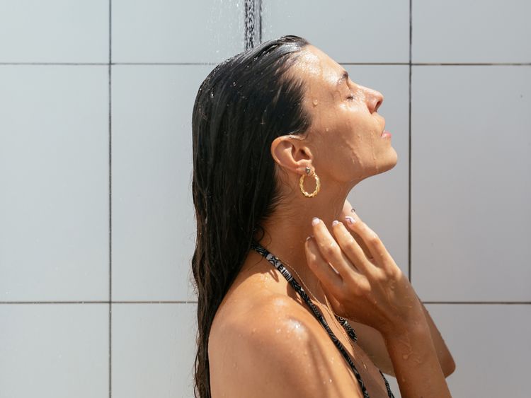 Mulher enxaguando o cabelo no chuveiro