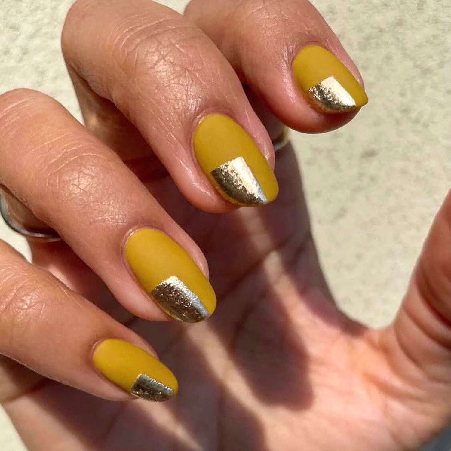 Manicure amarelo mostarda com desenho metálico cromado no canto da unha