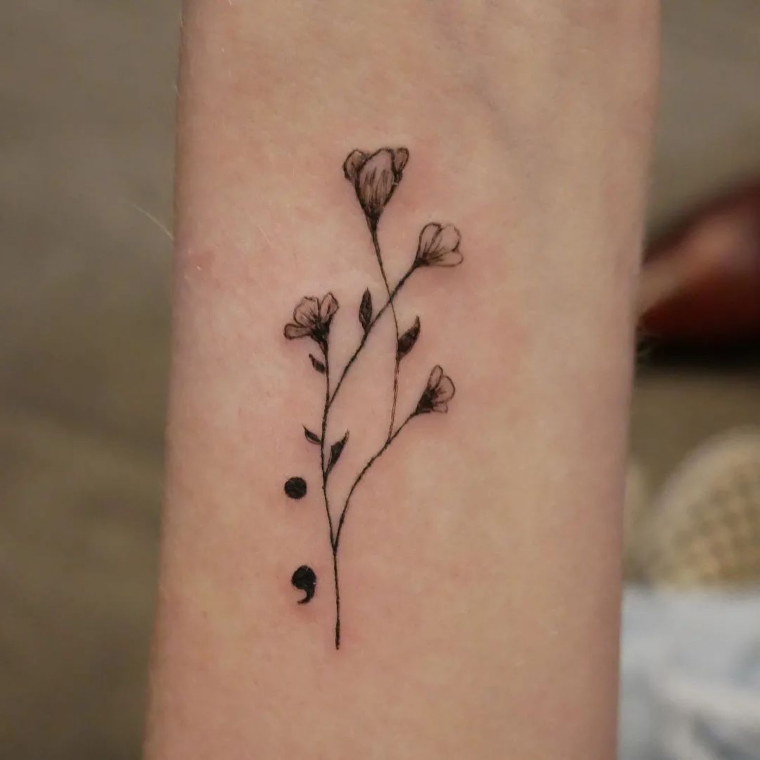 Tatuagem na forma de um ramo de flores representando um ponto de uma vírgula