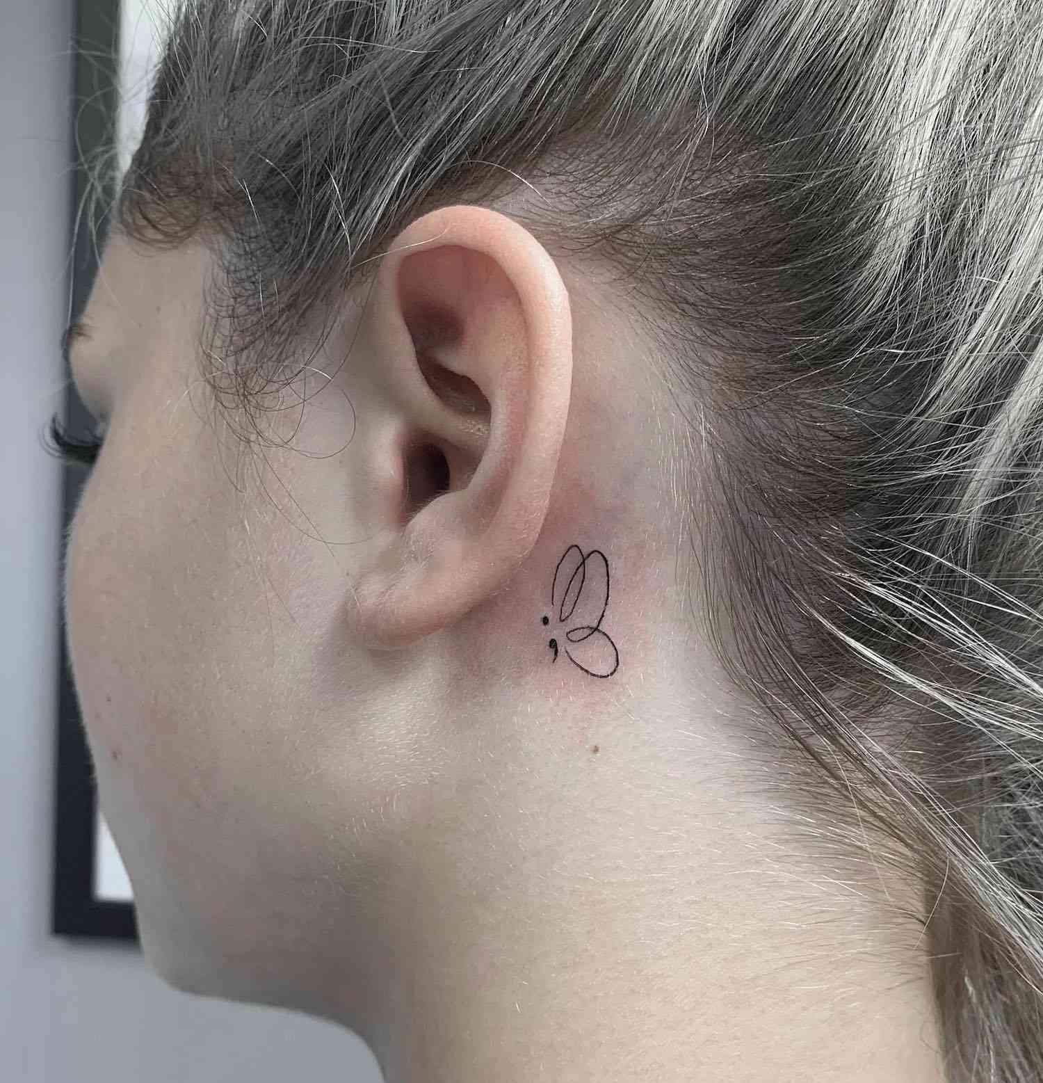 Fecha r-p -up Tattoo Butterfly com uma vírgula atrás da orelha de uma mulher