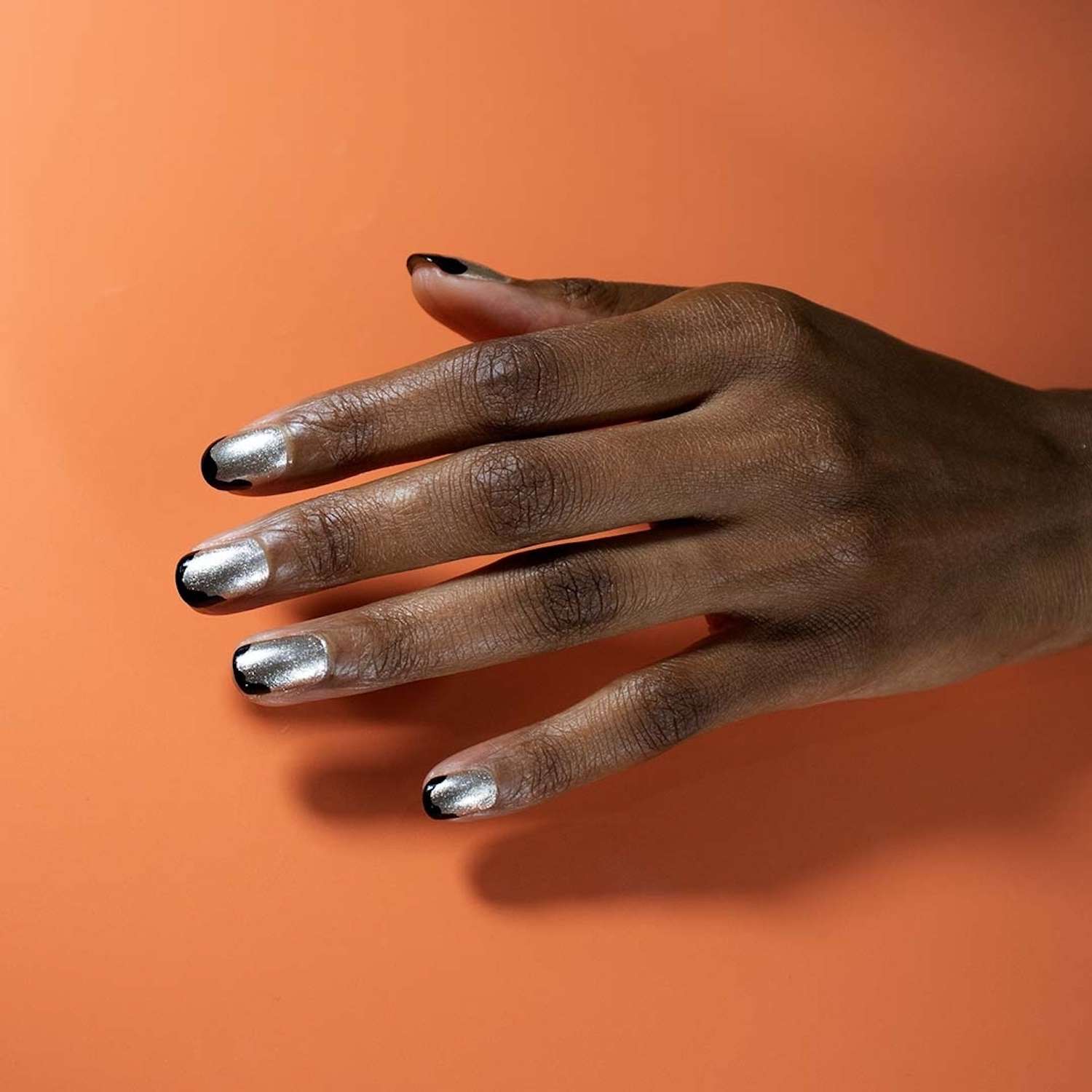 Manicure francesa negra com dicas onduladas e a base do brilho prateado