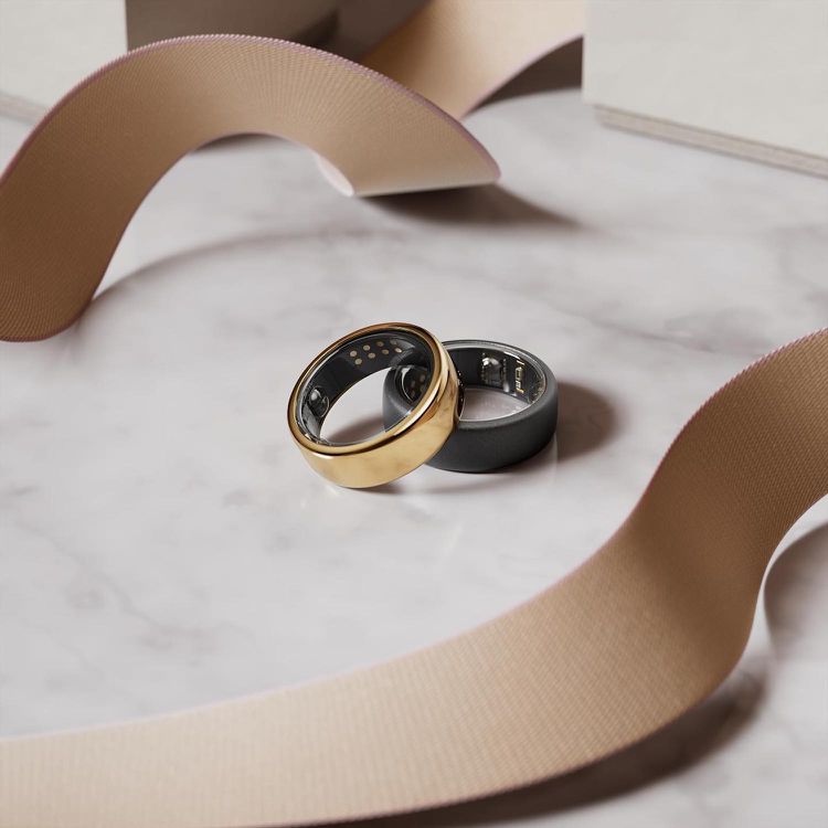 Dois anéis inteligentes, um, um ouro e um cinza, na mesa de mármore