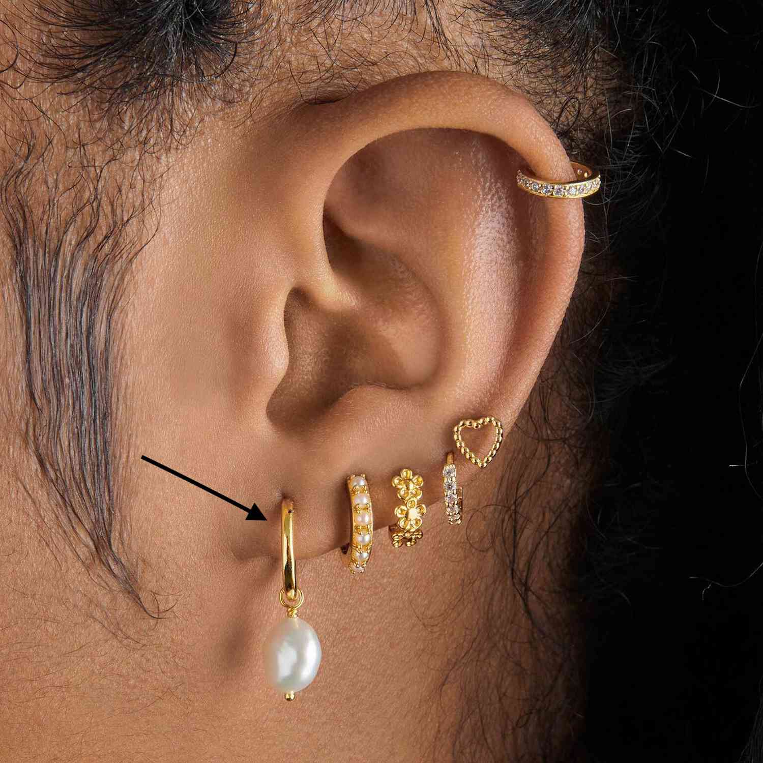 Close da orelha de um homem com muitos piercings dourados