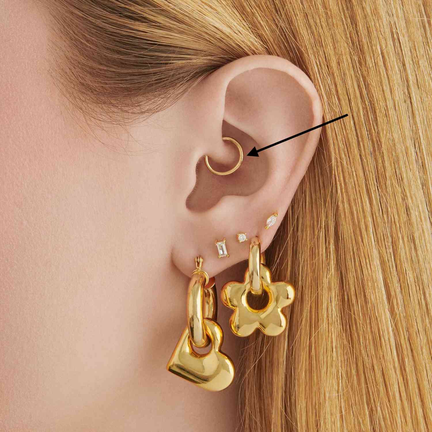close-up da orelha de uma mulher com piercing de ouro em dados