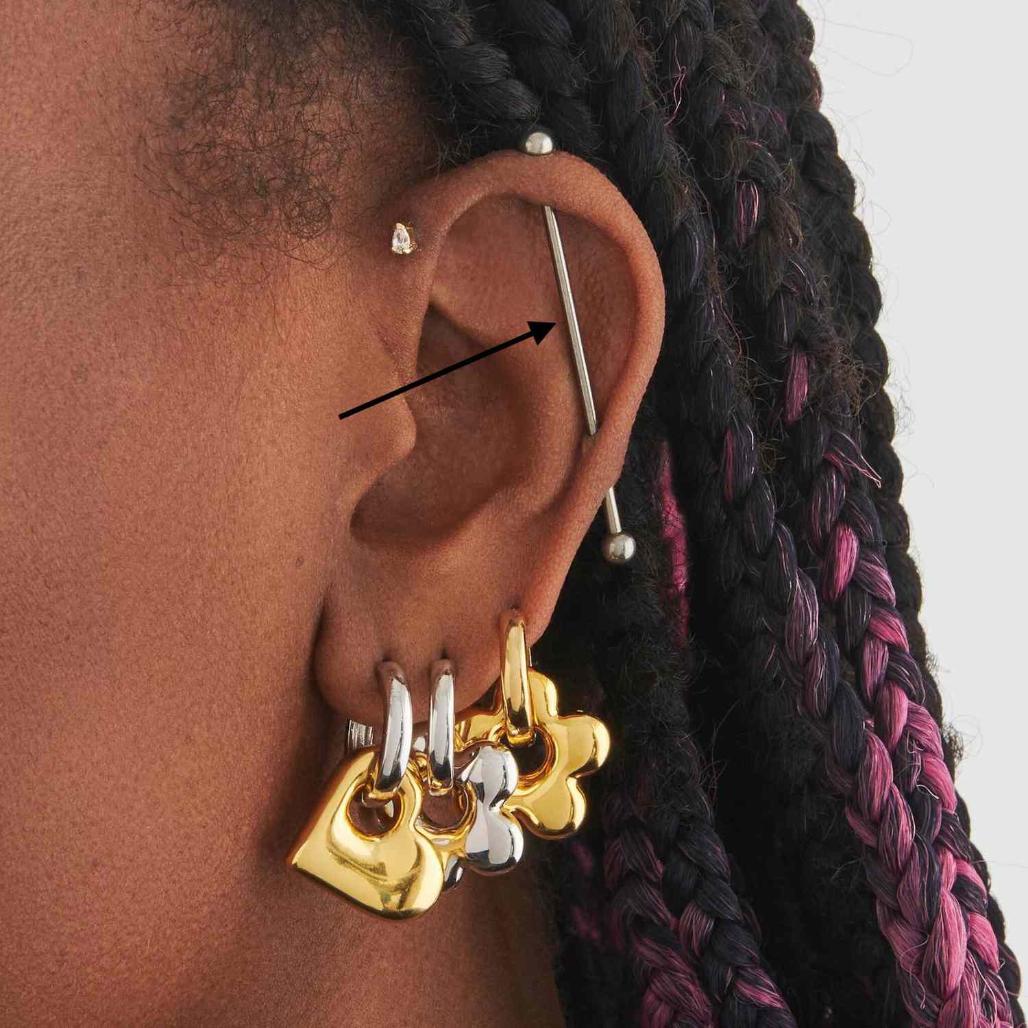 close da orelha de uma mulher com um piercing industrial prateado
