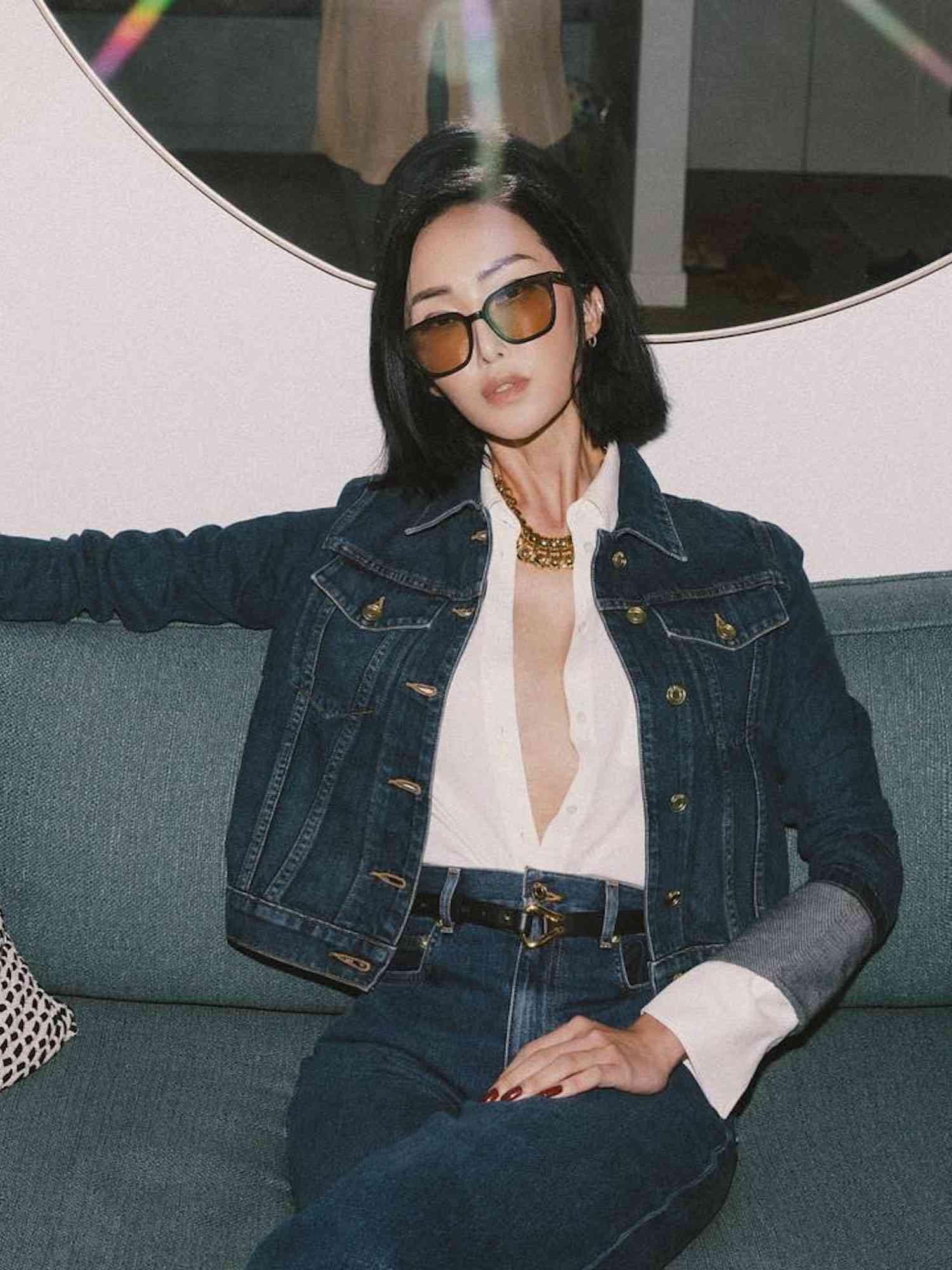 Chrisel Lim em uma camisa branca desabotoada, jaqueta jeans, jeans e óculos de sol matizados