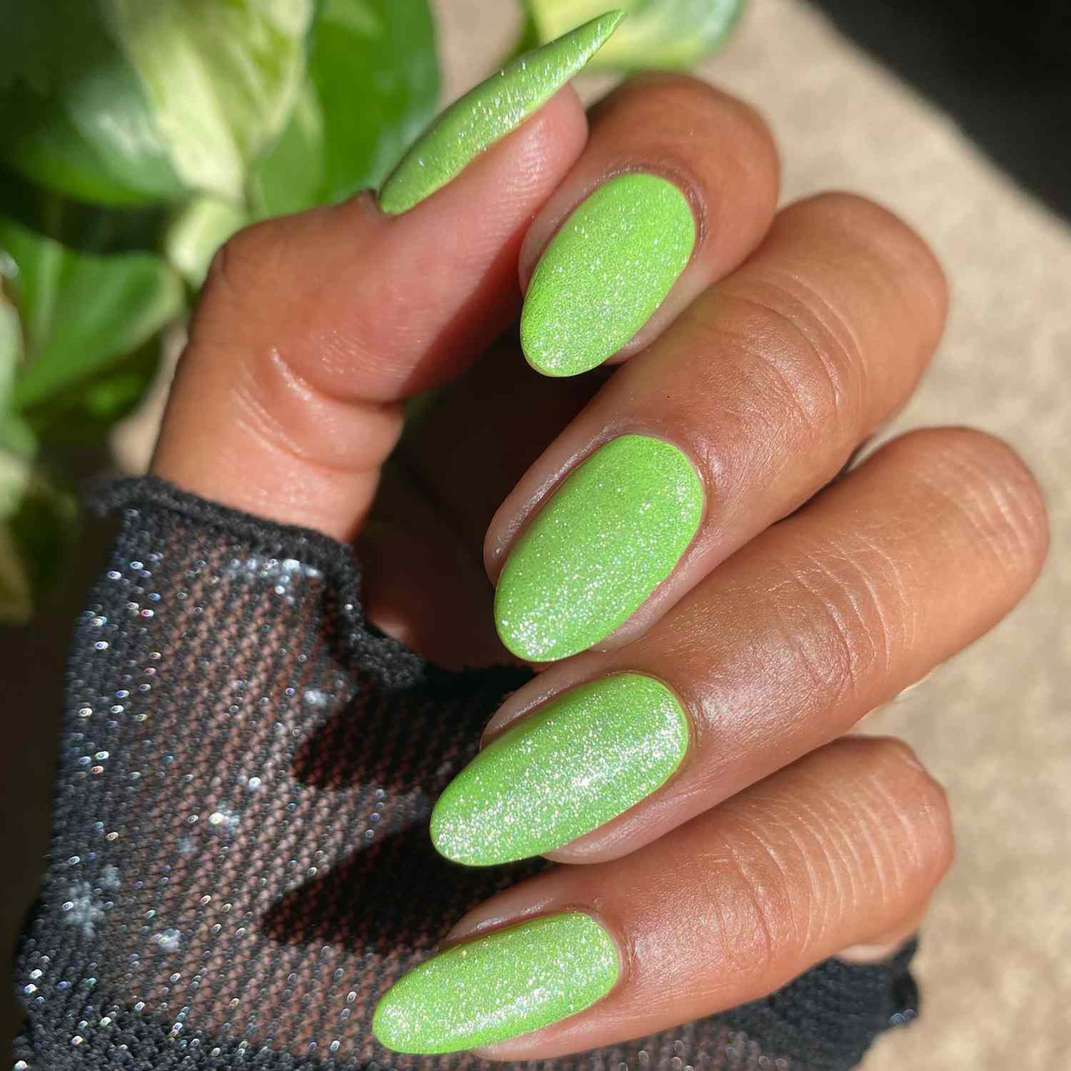 Close de uma manicure verde brilhante com um top coat glitter