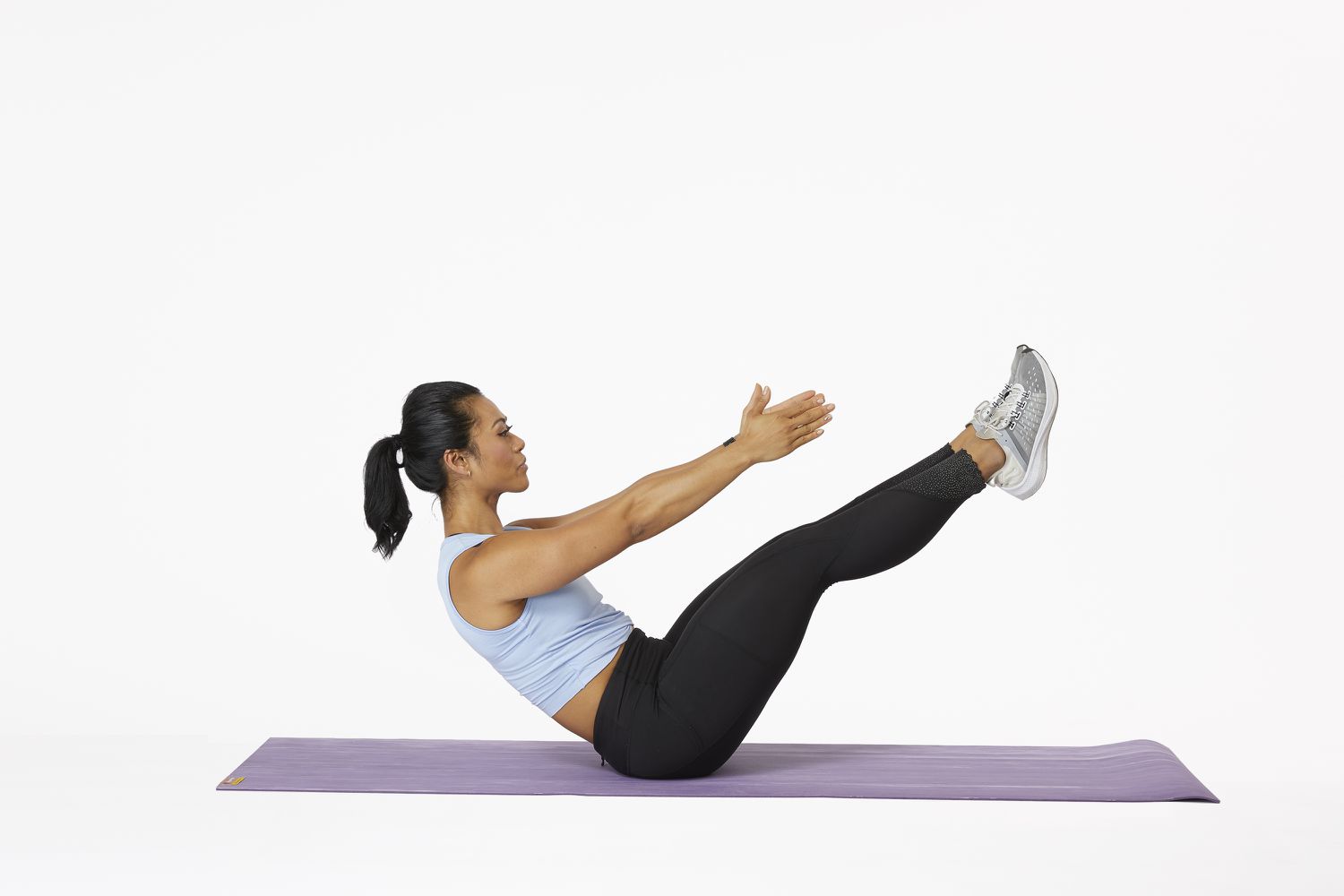 Uma mulher em um tapete de ioga realiza um exercício V-US