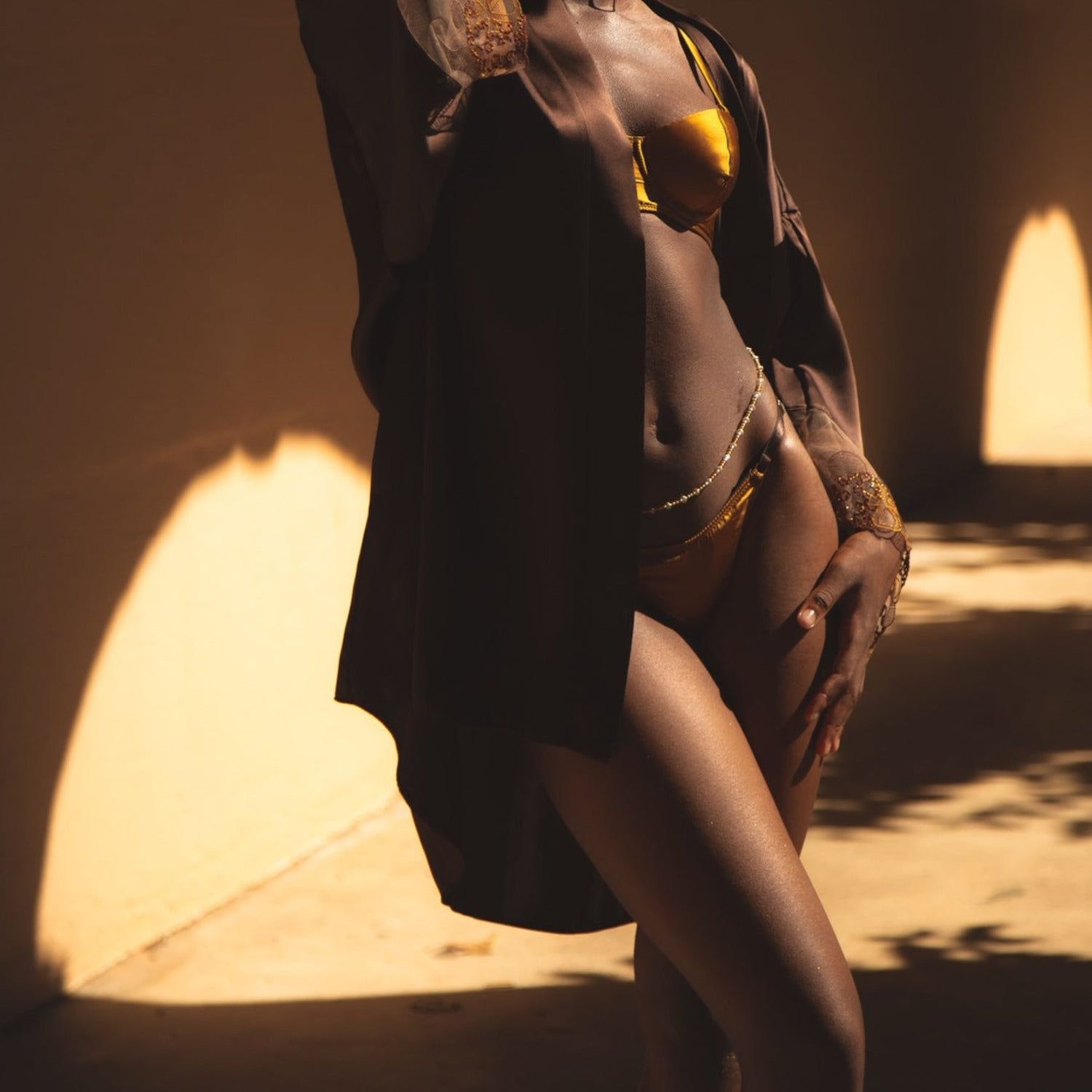 Modelo em conjunto de lingerie dourada e robe marrom escuro
