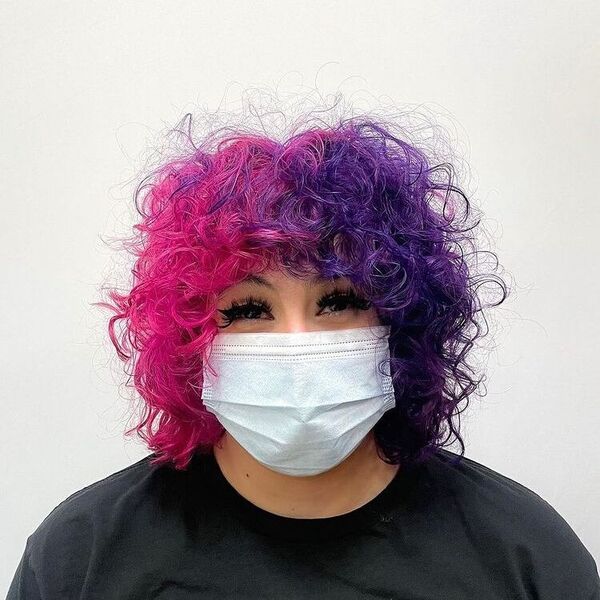 Cabelo rosa e roxo Curly dividido - uma mulher em uma máscara cirúrgica