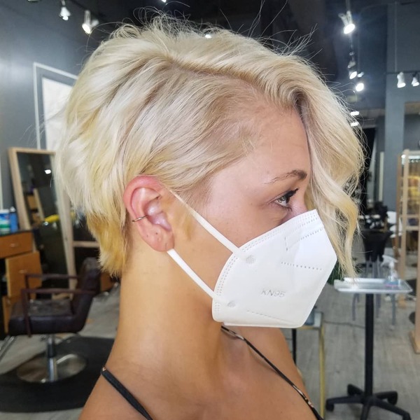 Corte de cabelo loiro - uma mulher em uma máscara branca KN95
