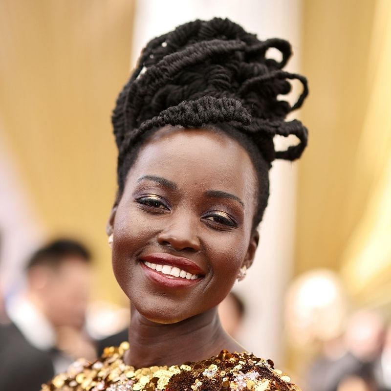 Lipit Njongo com um penteado com um bufão inclinado na cerimônia de premiação do Oscar 2022.