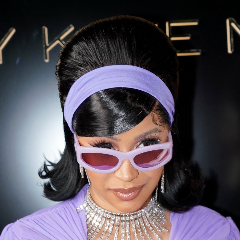 Cardi Bi em um penteado com um Buffan, com um curativo violeta na cabeça e os óculos de sol, bem como em roupas roxas e jóias de diamante na semana de moda em Paris, em 2021.