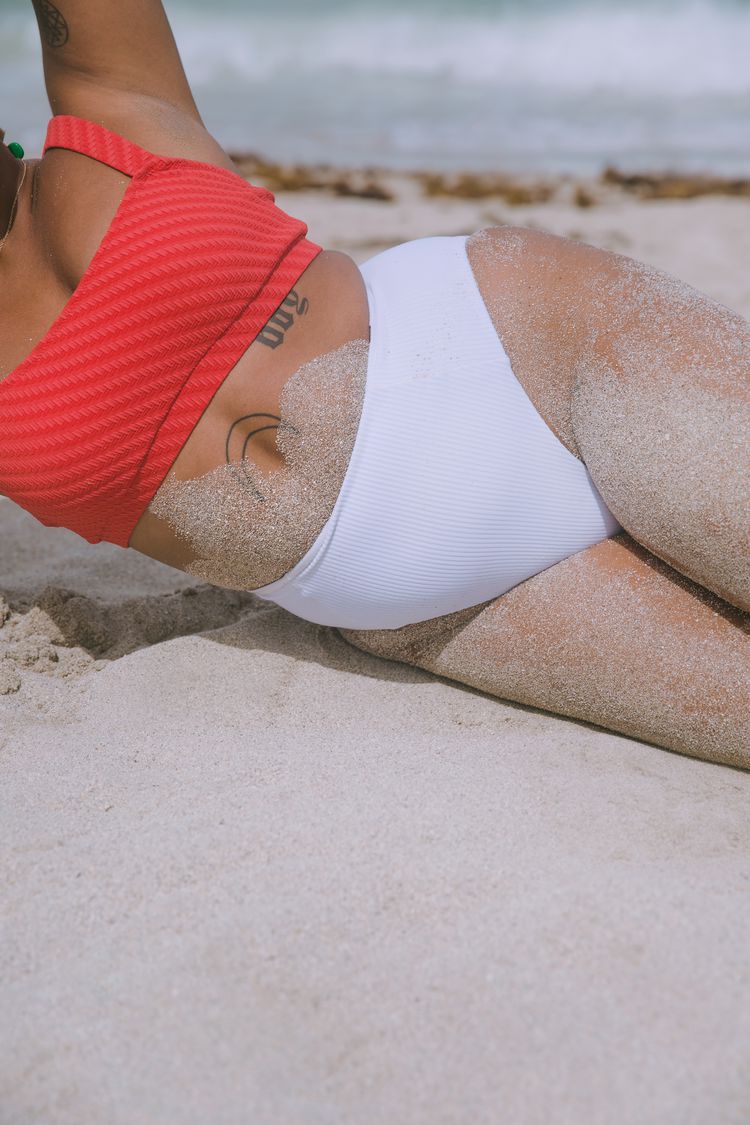 Uma mulher deita na areia em um biquíni