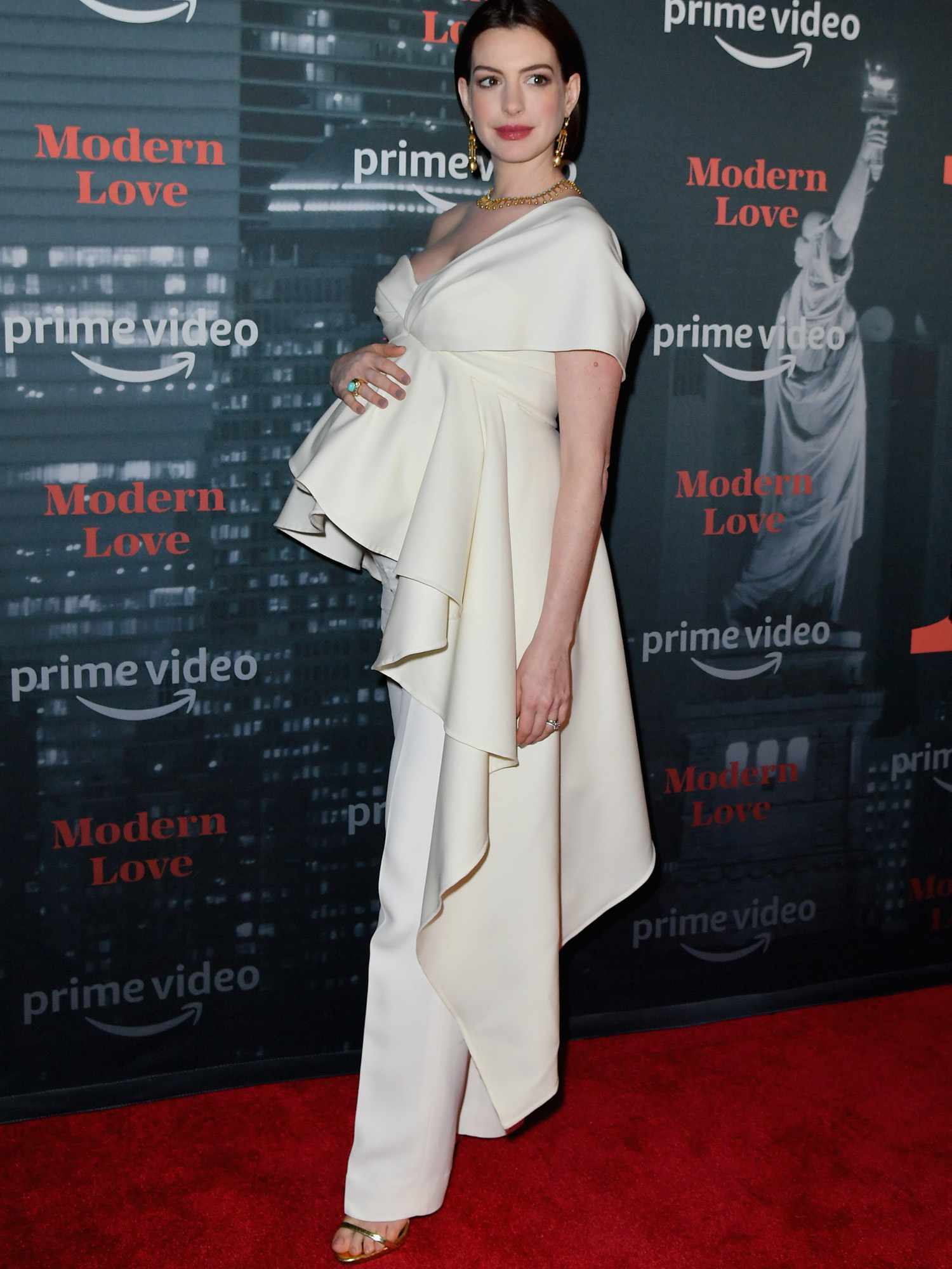 Anne Hathaway em um terninho branco assimétrico da Oscar de la Renta e joias de ouro