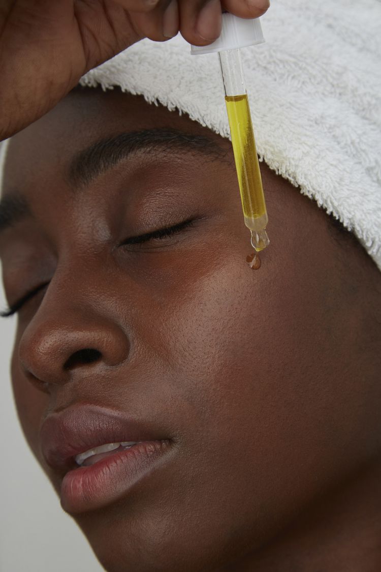 mulher aplicando óleo no rosto
