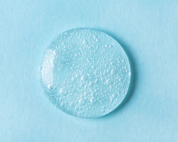 Uma gota de produtos para cuidados com a pele em um fundo azul