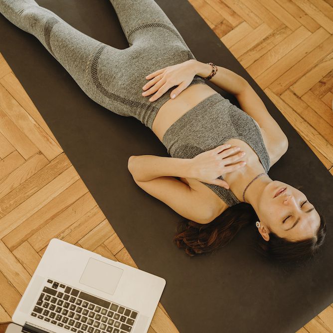 Uma mulher deita em um tapete de ioga em casa
