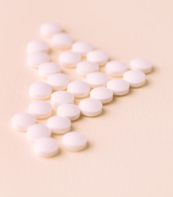 Close-up de comprimidos de biotina em fundo rosa claro