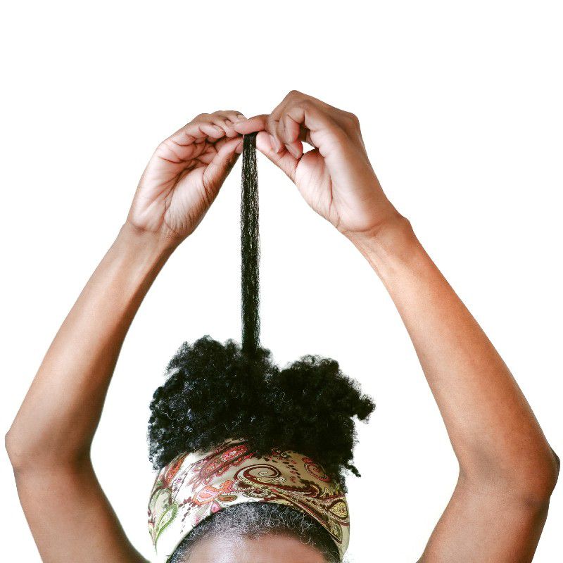 Uma mulher puxa alguns fios de seu cabelo natural para cima