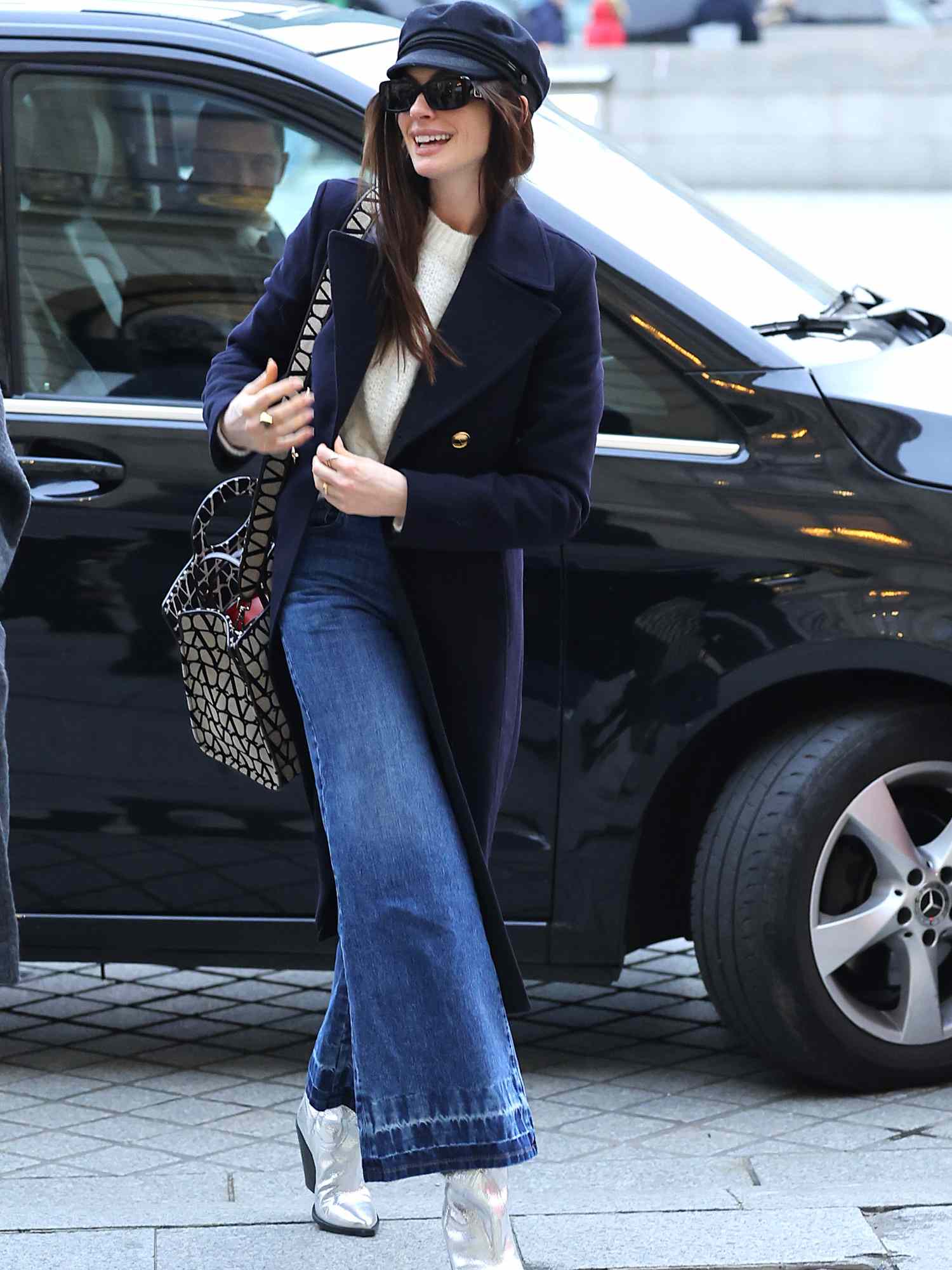 Anne Hathaway em jeans, um casaco de lã escura e botas de prata