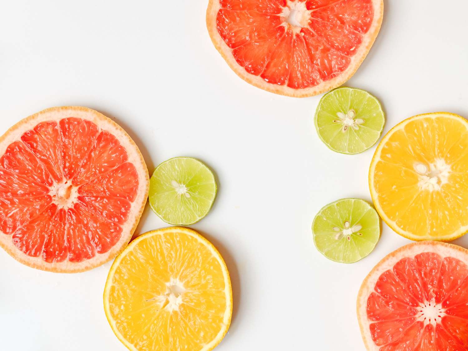 Imagem aproximada de fatias de frutas cítricas (toranja, limão e laranja) em cima da mesa