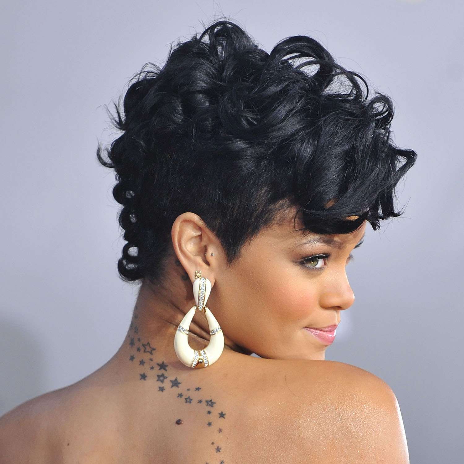 Rihanna com cabelo curto cacheado e tatuagem de estrela nas costas