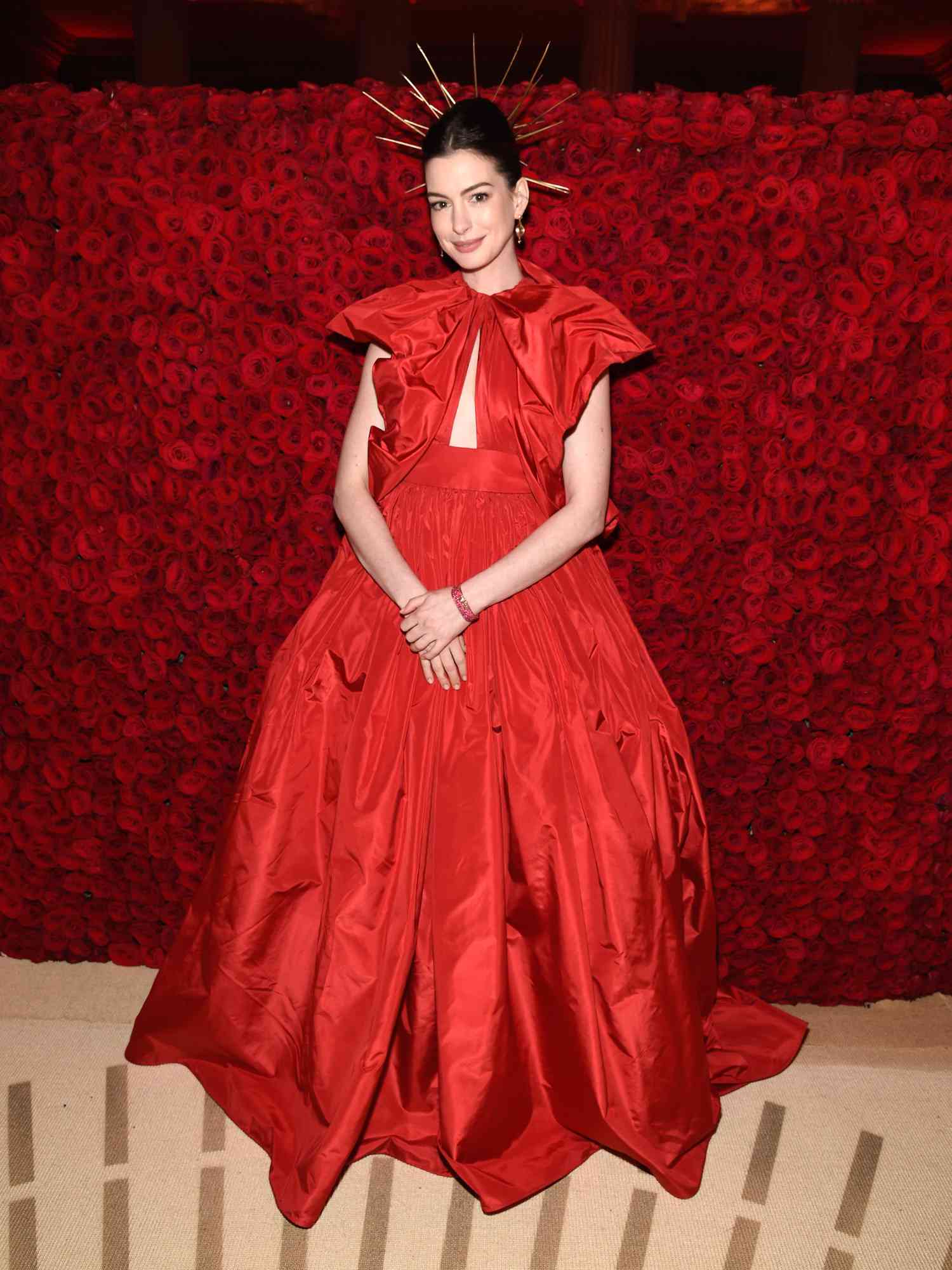 Anne Hathaway em um vestido de baile Valentino vermelho e capacete celestial dourado no Met Gala