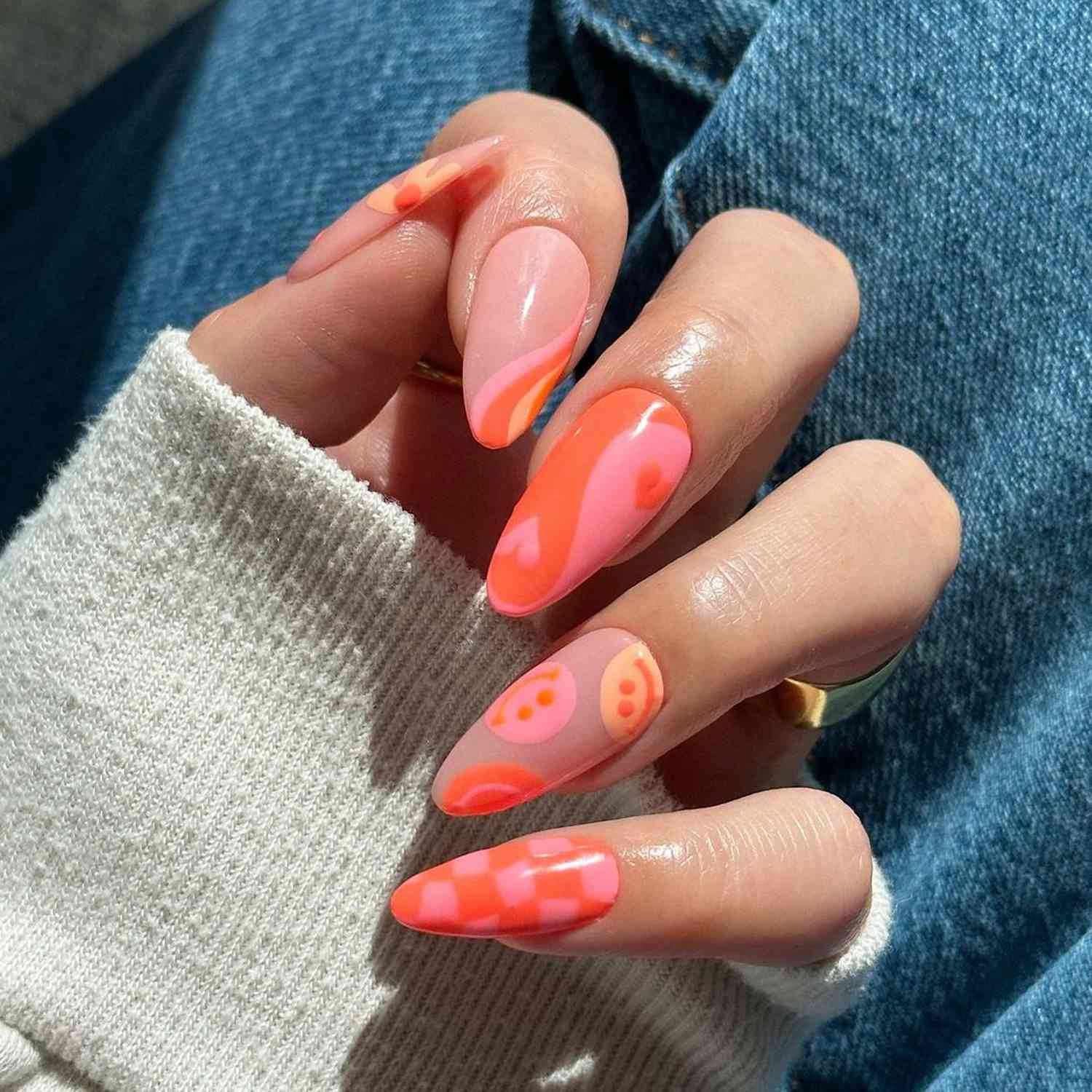 Design rosa laranja de unhas com muitos padrões em unhas em forma de amêndoa