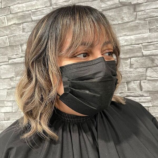Balayage ondulada multicamada com franja - uma mulher em uma capa preta e uma máscara