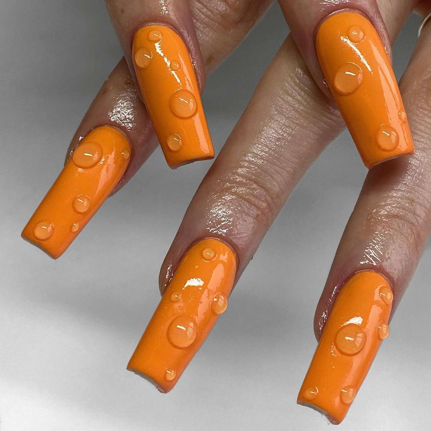 Gotas de orvalho laranja em unhas na forma de um caixão