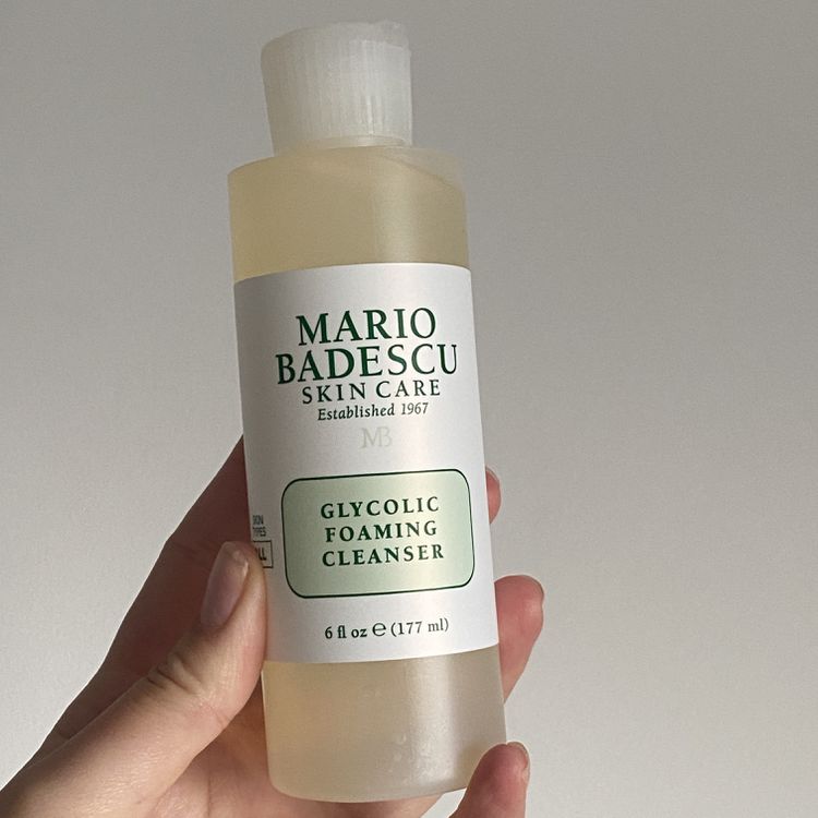 A mão segura a garrafa Mario Badescu Glicolic Foming Cleanser