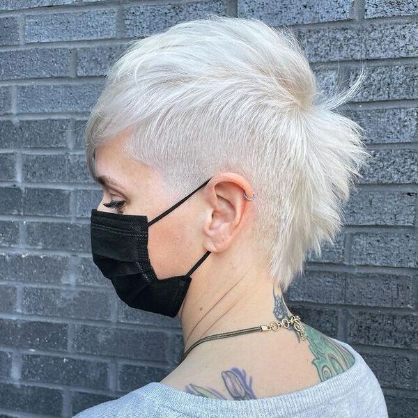 Pixie Platinum Haircut - Uma mulher com uma tatuagem em uma máscara preta