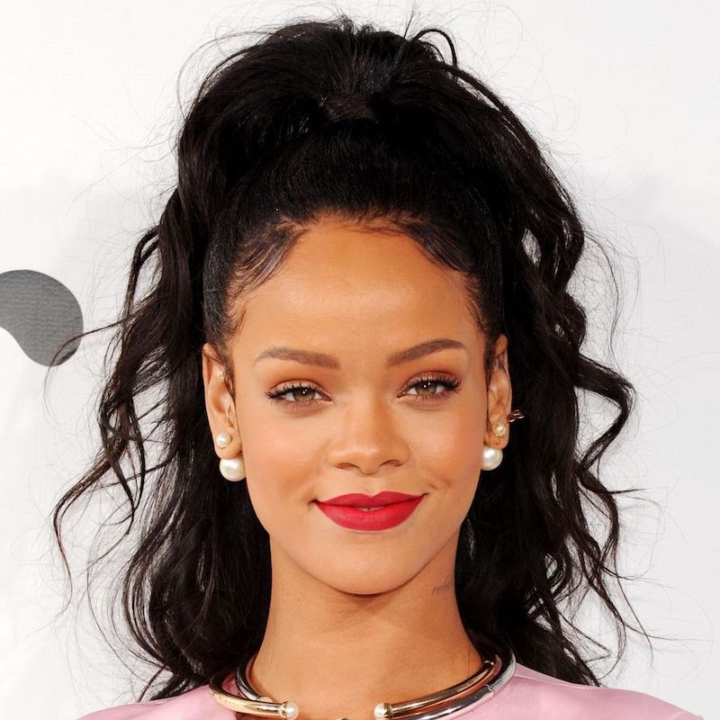 Rihanna coloca seus cabelos encaracolados em um penteado com uma cauda meio para cima, meio para baixo