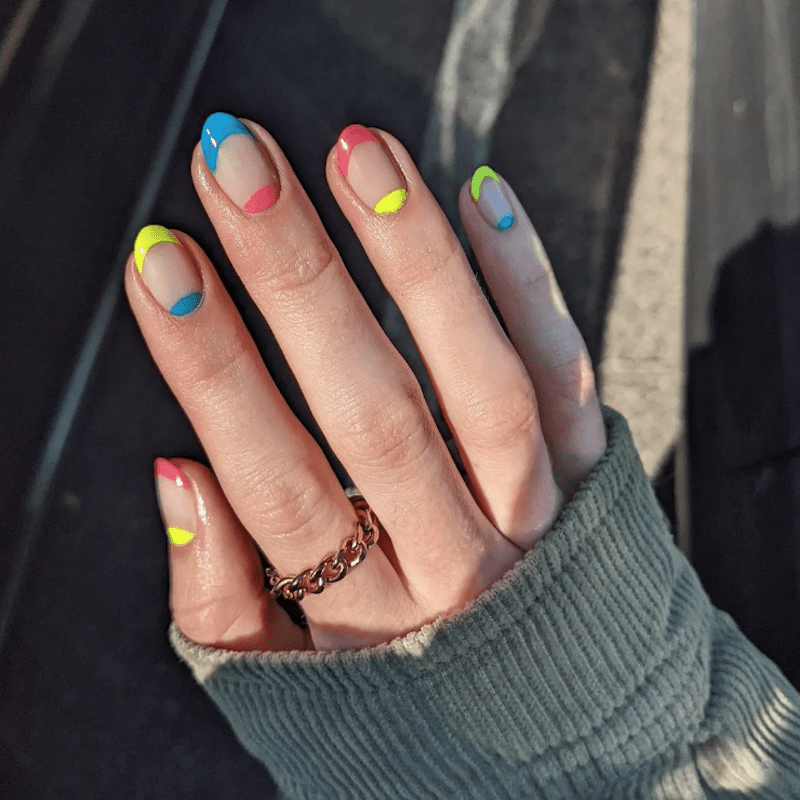 Manicure francesa amarela, azul e rosa com um design de sem i-lua