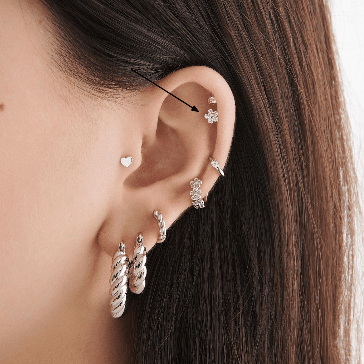 Vista lateral da orelha de uma mulher com muitos piercings