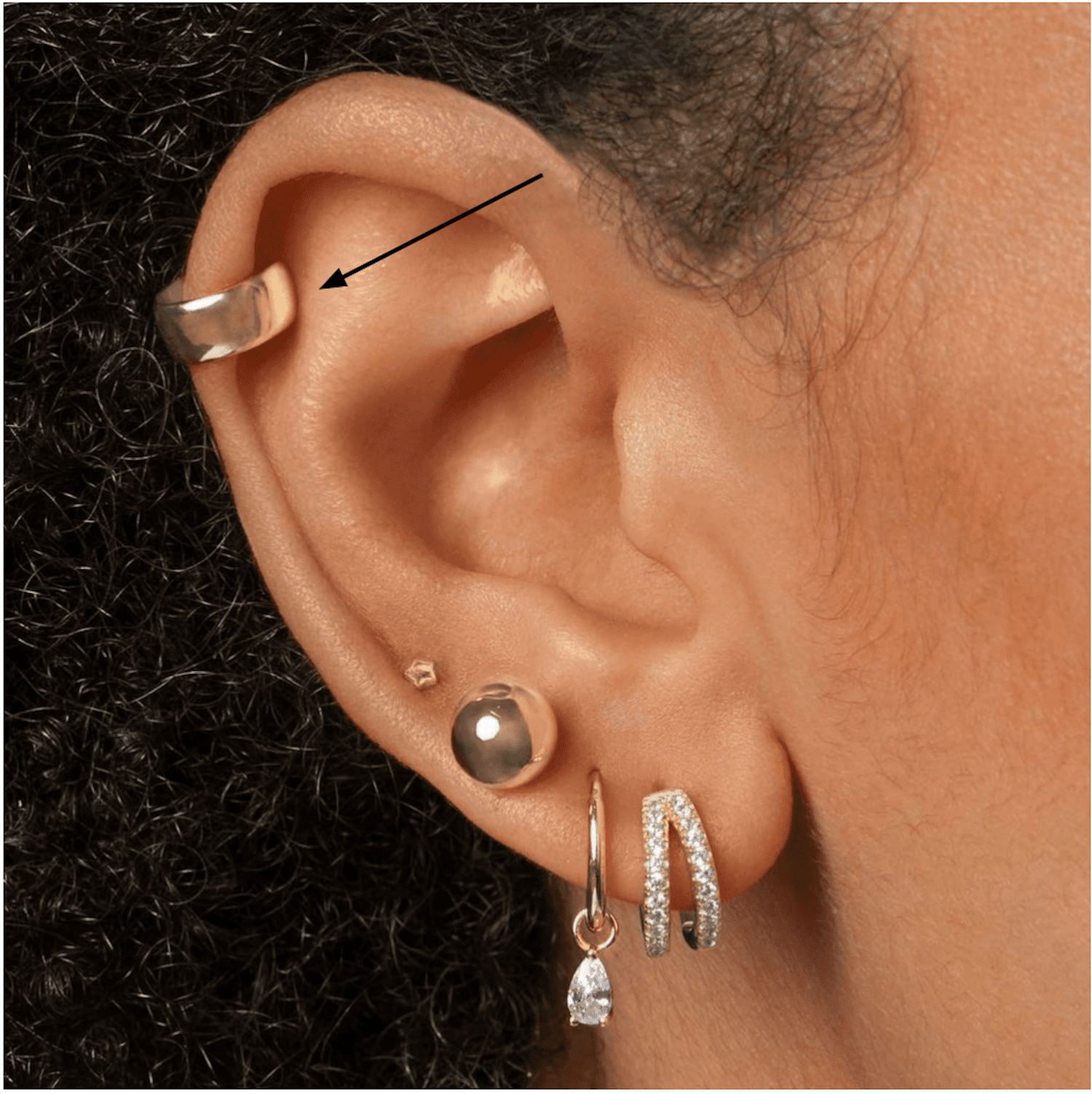 Vista lateral da orelha de uma mulher com um piercing espiral dourado