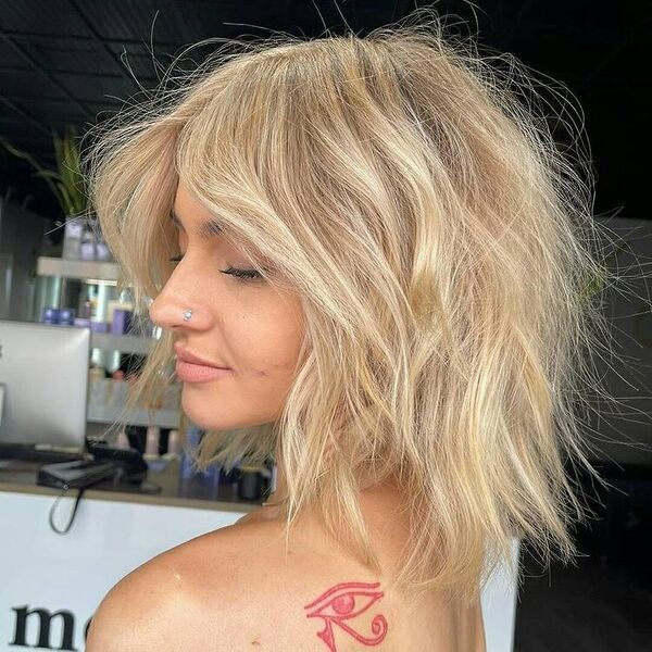 Cabelo curto com raízes loiras platinadas - mulher com tatuagem de olho nas costas do ombro