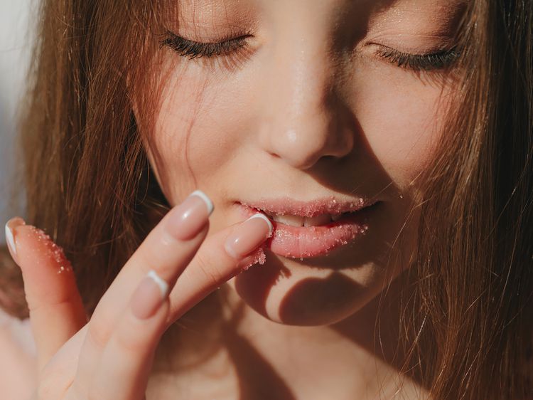 Fecha r-se mulher aplicando esfoliação de açúcar nos lábios