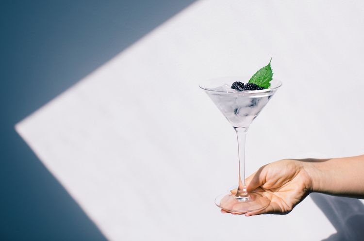 Bebida alcoólica transparente em um vidro de martini decorado com mirtilos