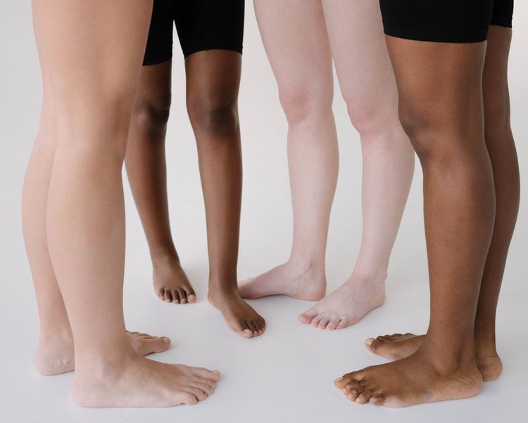 O fechament o-up das pernas de quatro mulheres com um tom de pele diferente e o tipo de figura