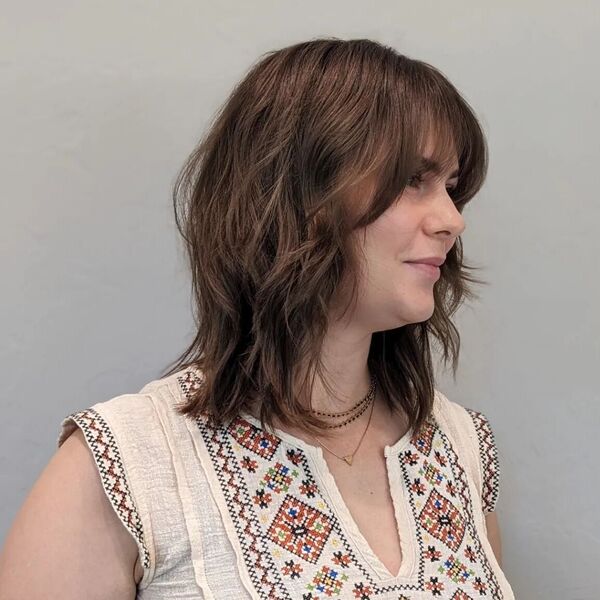Cabelo ondulado com franja - uma mulher em uma camiseta bege com uma impressão