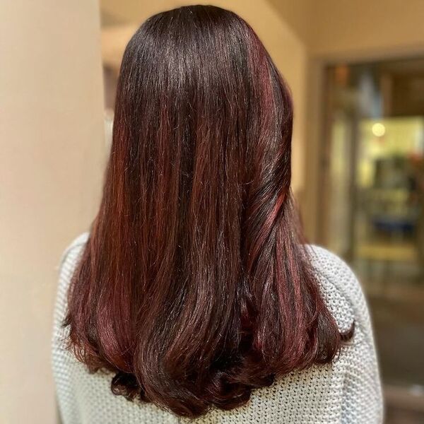 Sombra marrom-avermelhada com um corte de cabelo em forma de U é uma mulher em uma blusa de malha branca.