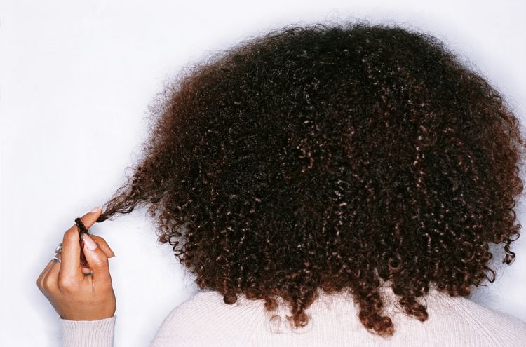Uma mulher espalhando um enrolamento de cabelos encaracolados