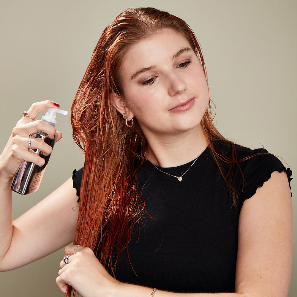 Uma mulher aplica uma ferramenta de proteção ao calor para cabelos molhados