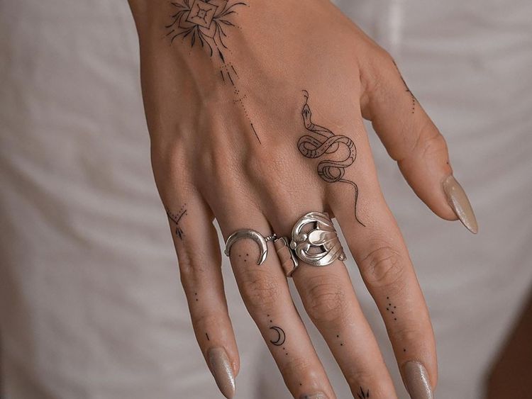 Close de uma mão com muitas pequenas tatuagens