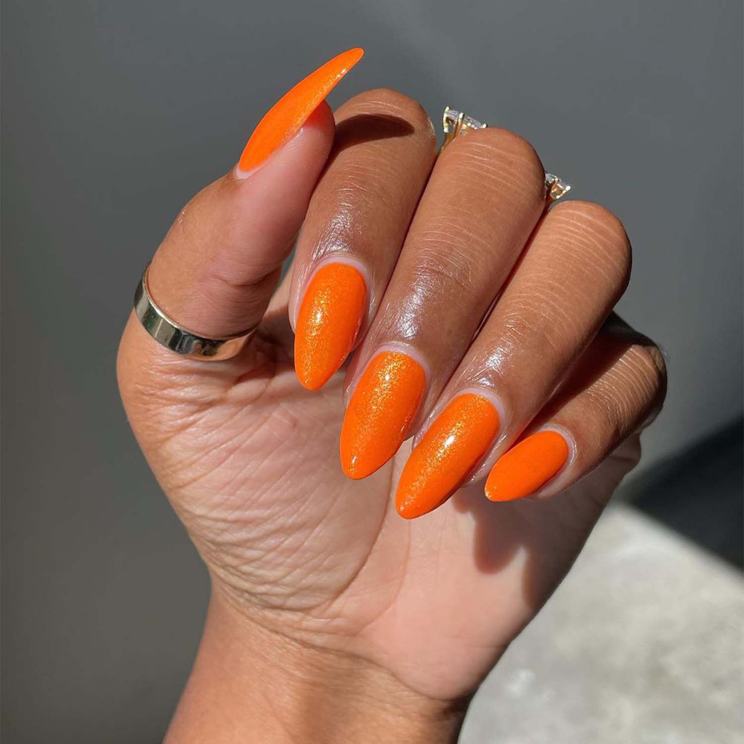 mão feminina com unhas laranja de manga