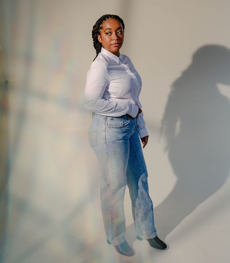 Uma mulher negra esbelta em jeans e uma camisa branca