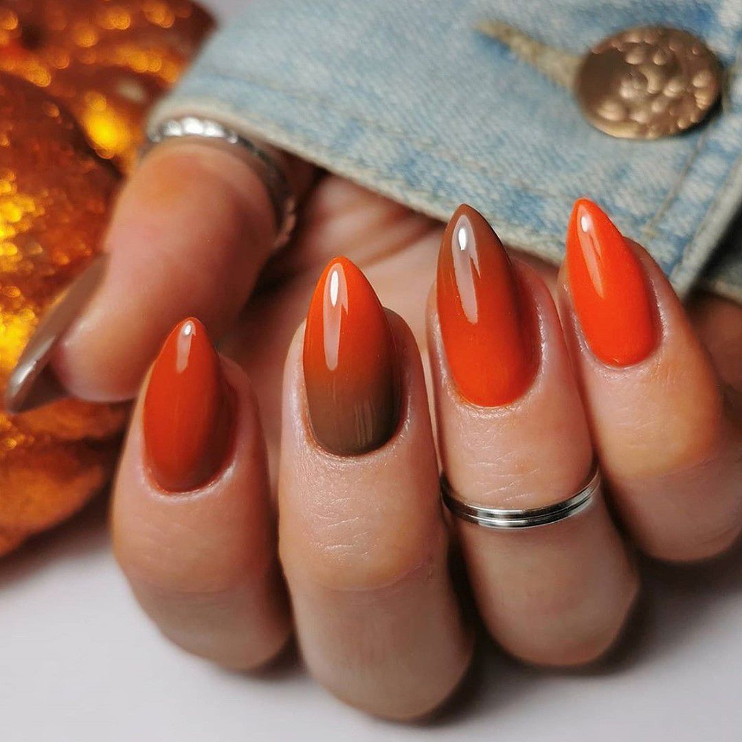 Mão em close-up com ombre marrom-laranja em unhas